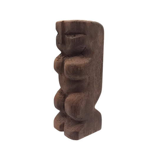 Side view of a Hawaiian wooden tiki sculpture on a white background