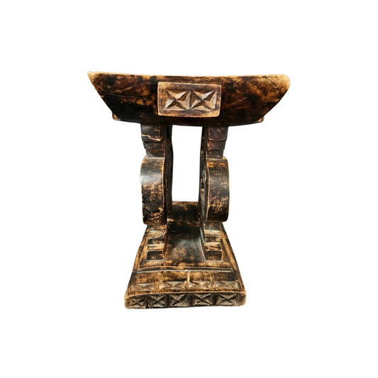 Side view of a wooden stool with a unique design on a white background