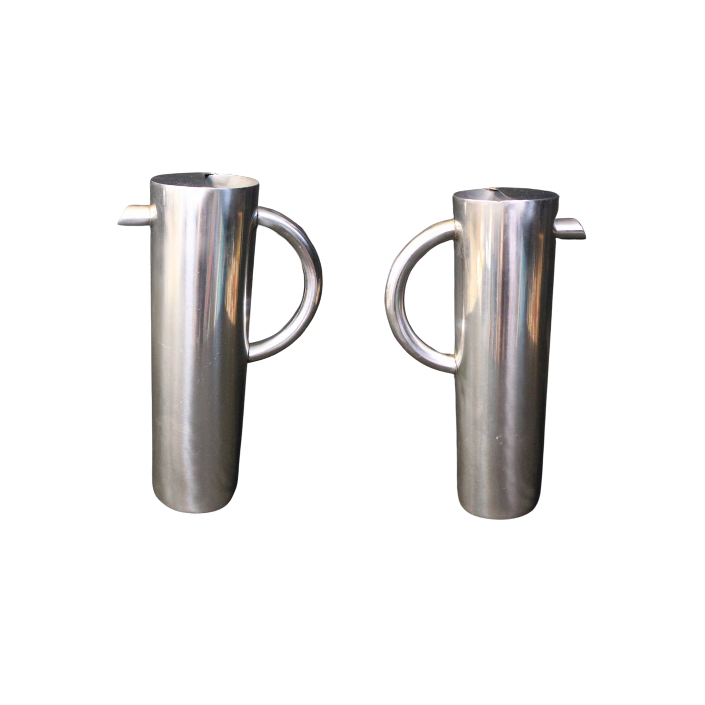 Attention all collectors and design enthusiasts! Introducing our sleek and rare water pitcher, with a modern Industrial design and impressive size. This tall and shiny stainless-steel cylinder holds 60 ounces of refreshing tap or bottled water, featuring a convenient "C" handle and angled spout for a stylish pour. Get yours today before it's gone!