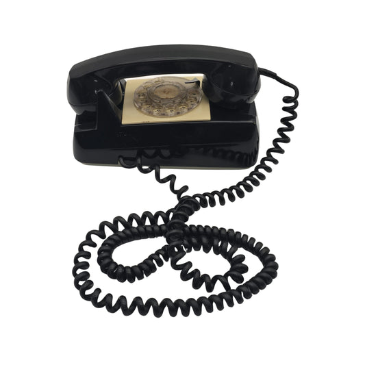 Side view of a vintage black wall phone with a coiled cord on a white background
