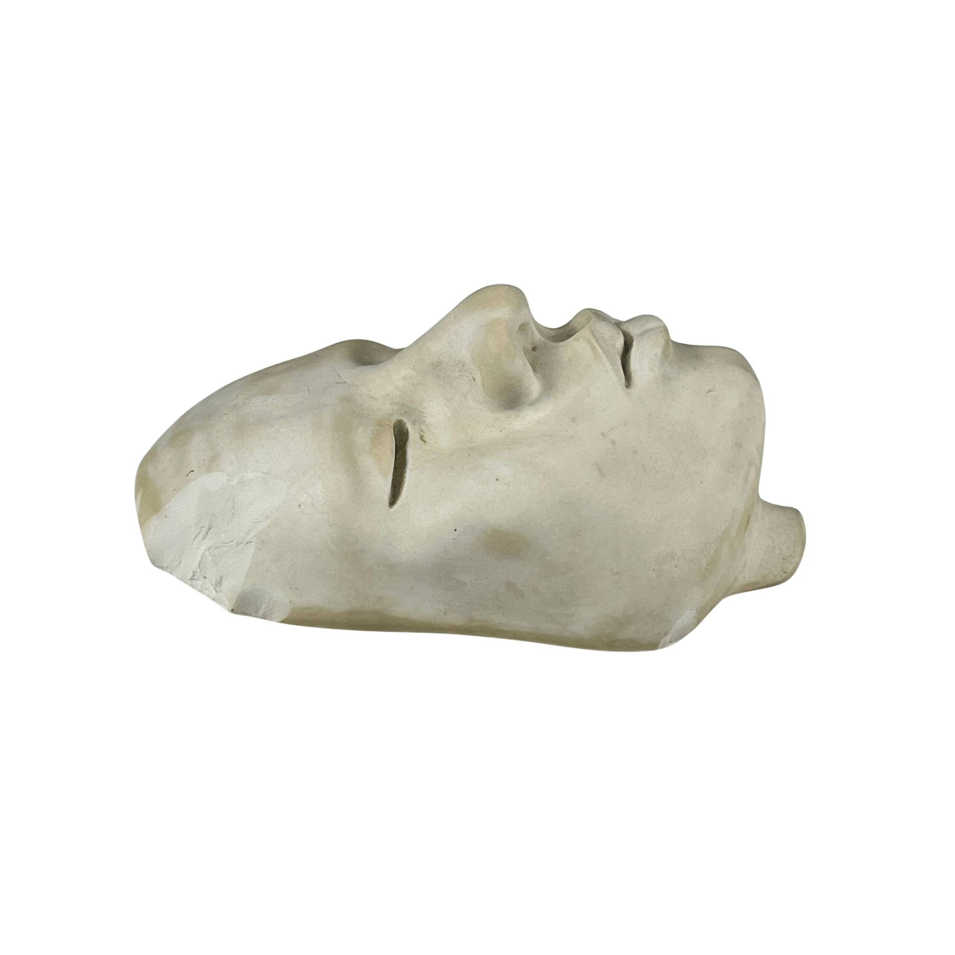 Side view of a plaster sculpture of a face on a white background