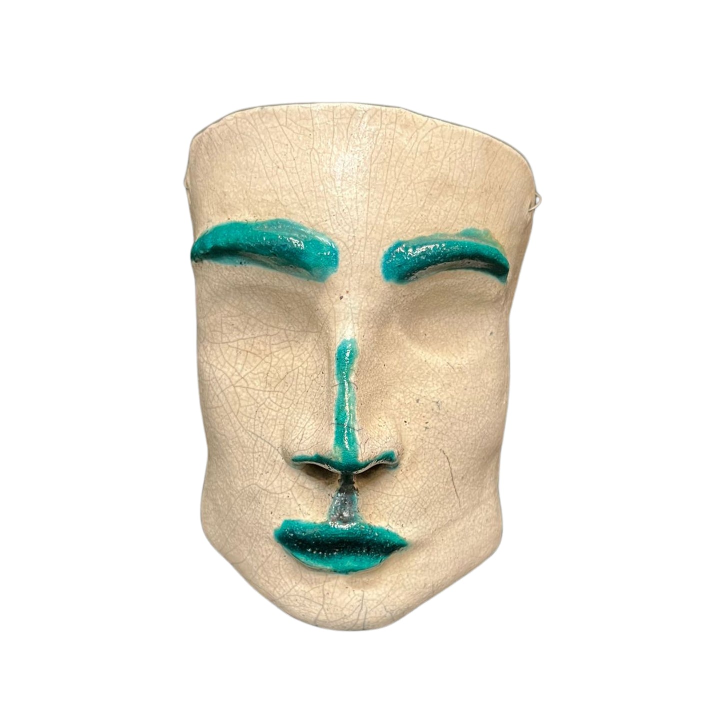 Front view of a ceramic face sculpture with teal accents on a white background