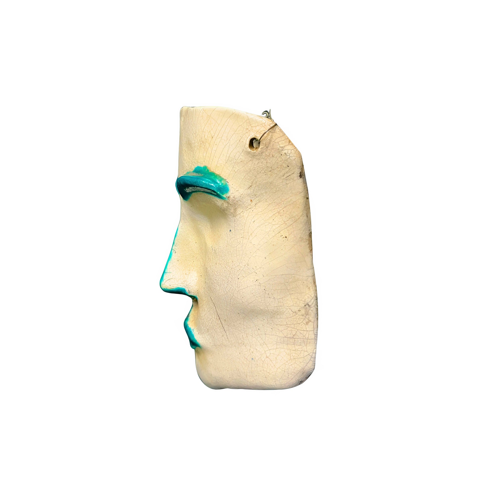 Side view of a ceramic face sculpture with teal accents on a white background