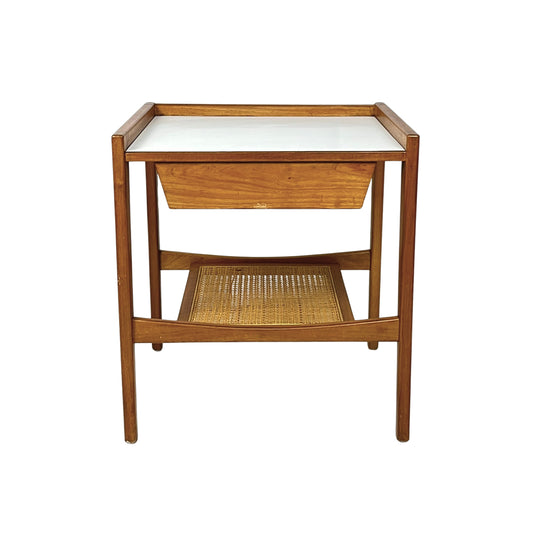 Wooden side table with a white top and wicker shelf on a white background
