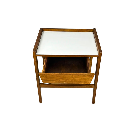 top view of a wooden side table with a white top and wicker shelf, with an open drawer, on a white background