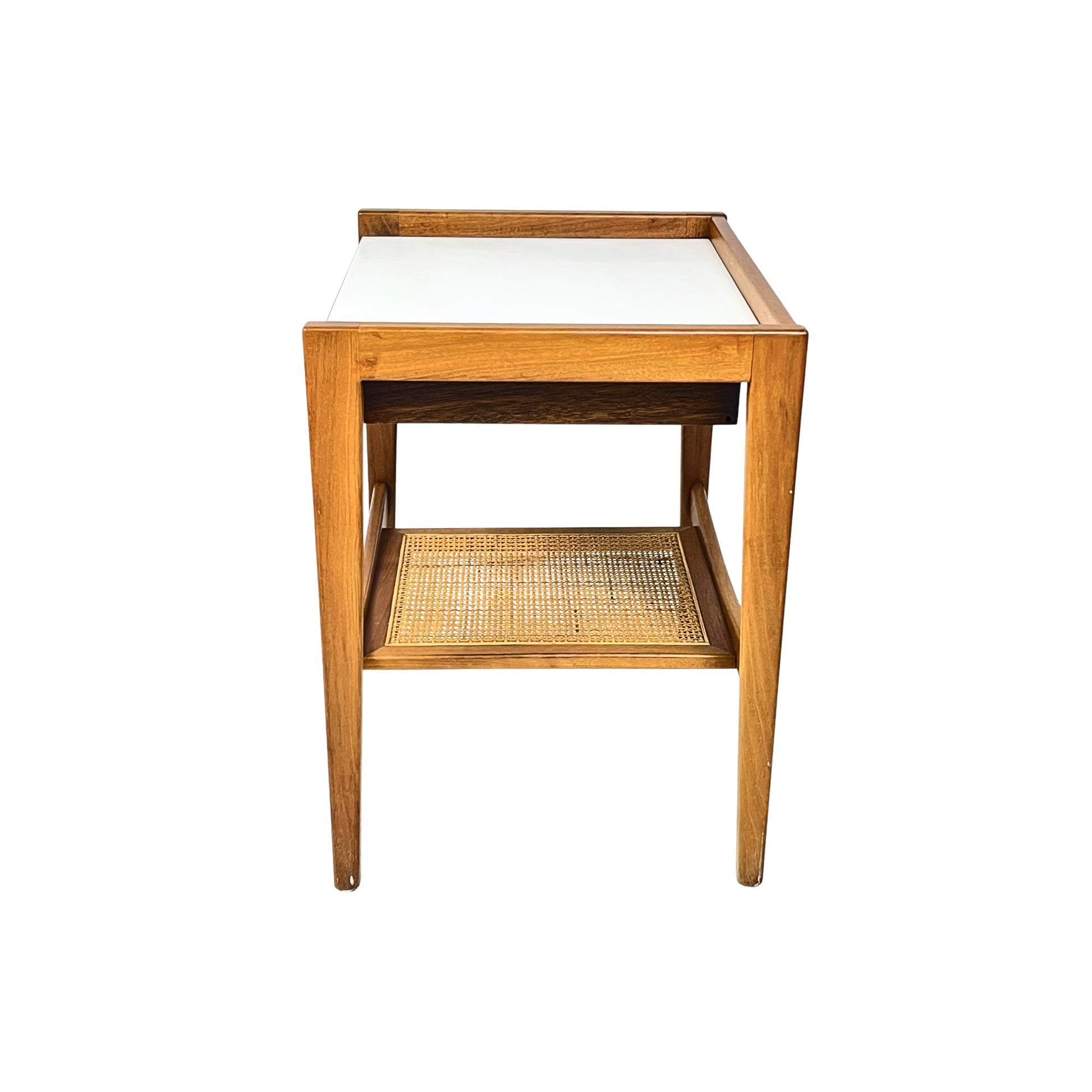 side view of a wooden side table with a white top and a wicker shelf on a white background