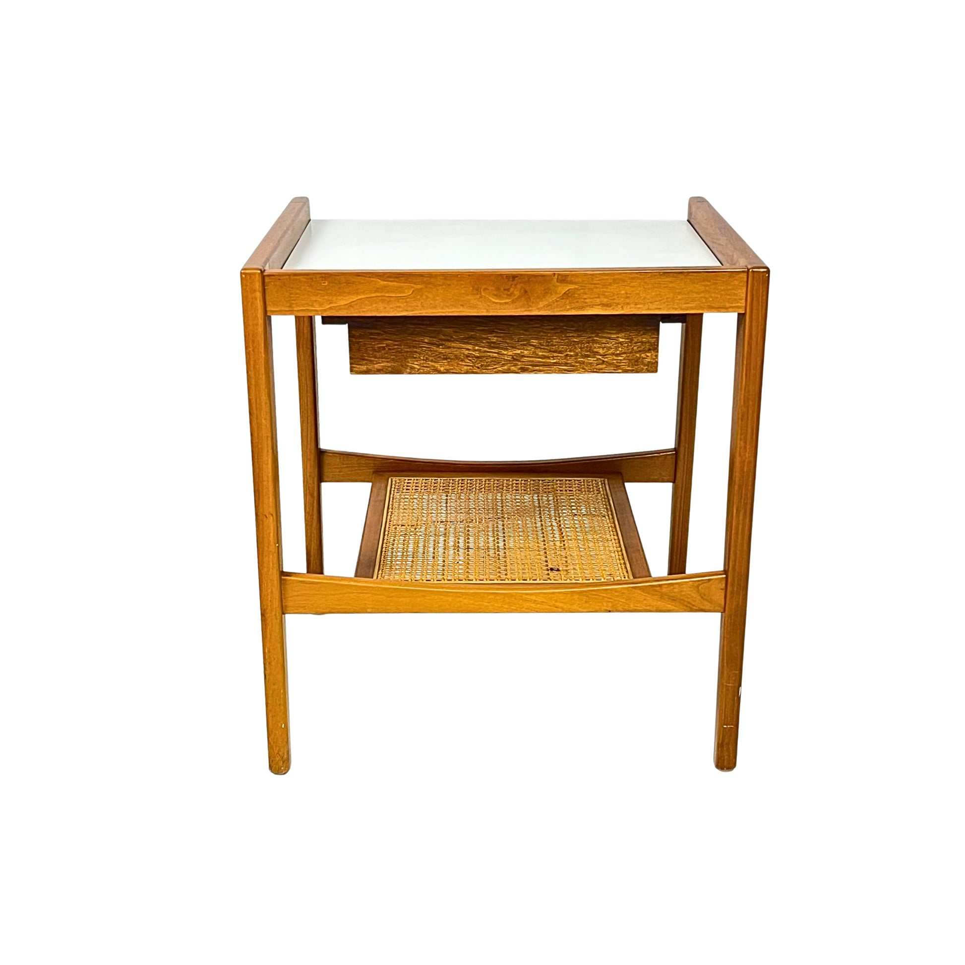 Back view of a wooden side table with a white top and a wicker shelf on a white background