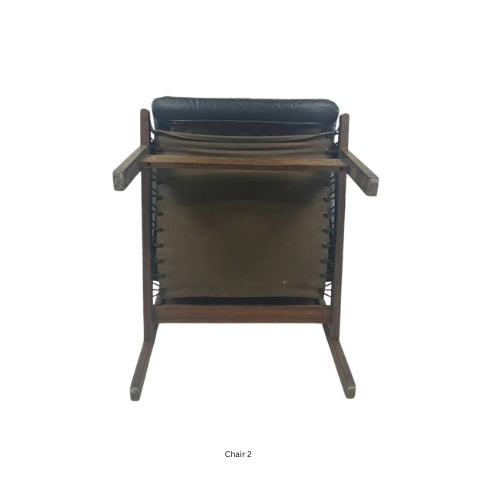 Bottom view of a vintage mid‑century modern lounge chair with dark tufted leather cushions and a sculpted wooden frame
