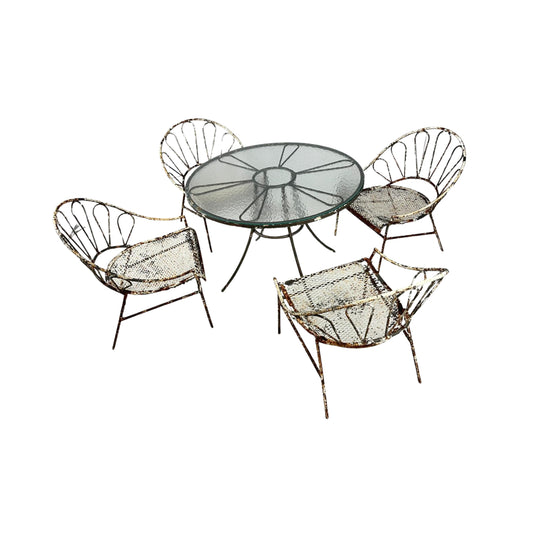 View of a round iron table set with a glass top and 4 wrought iron chairs on a white background