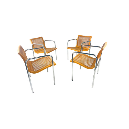 Four natural wood-colored and cesca chairs with metal frames on a white background