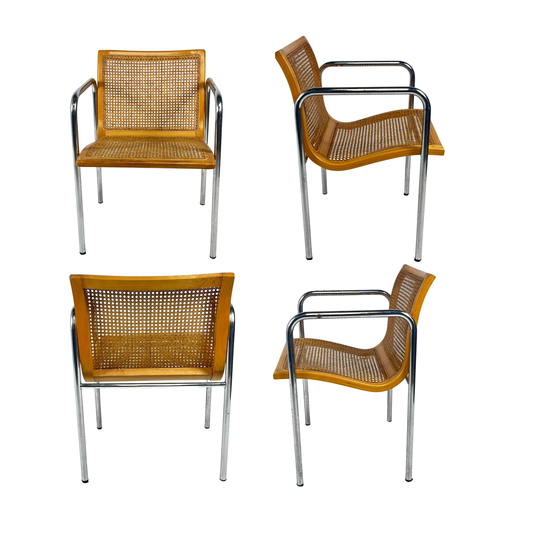 Four chairs with wicker seats and metal frames on a white background