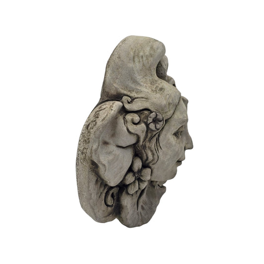 Side view of decorative stone wall plaque with face and floral design on white background